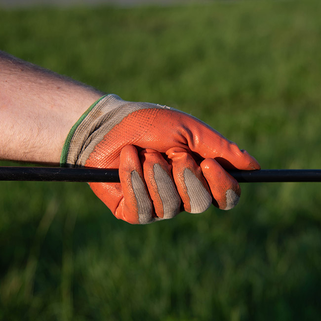 Close up of a mans hand with a glove on holding a fiber cable
